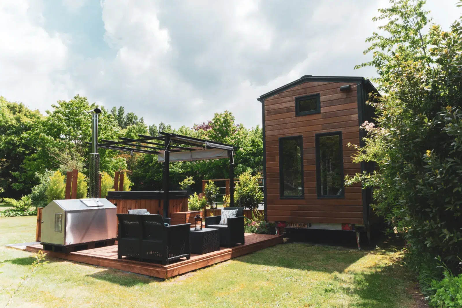Gîte moderne en bois avec terrasse aménagée, jacuzzi et pergola dans un jardin
