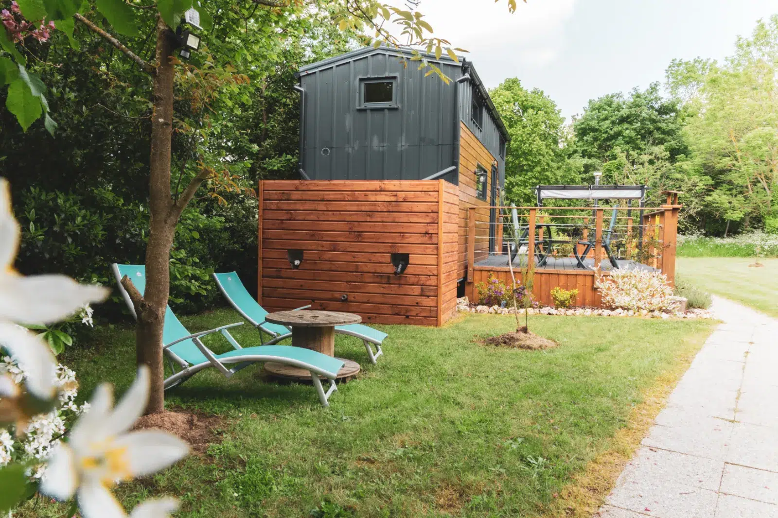 Terrasse en bois avec transats et jardin autour d’un gîte moderne