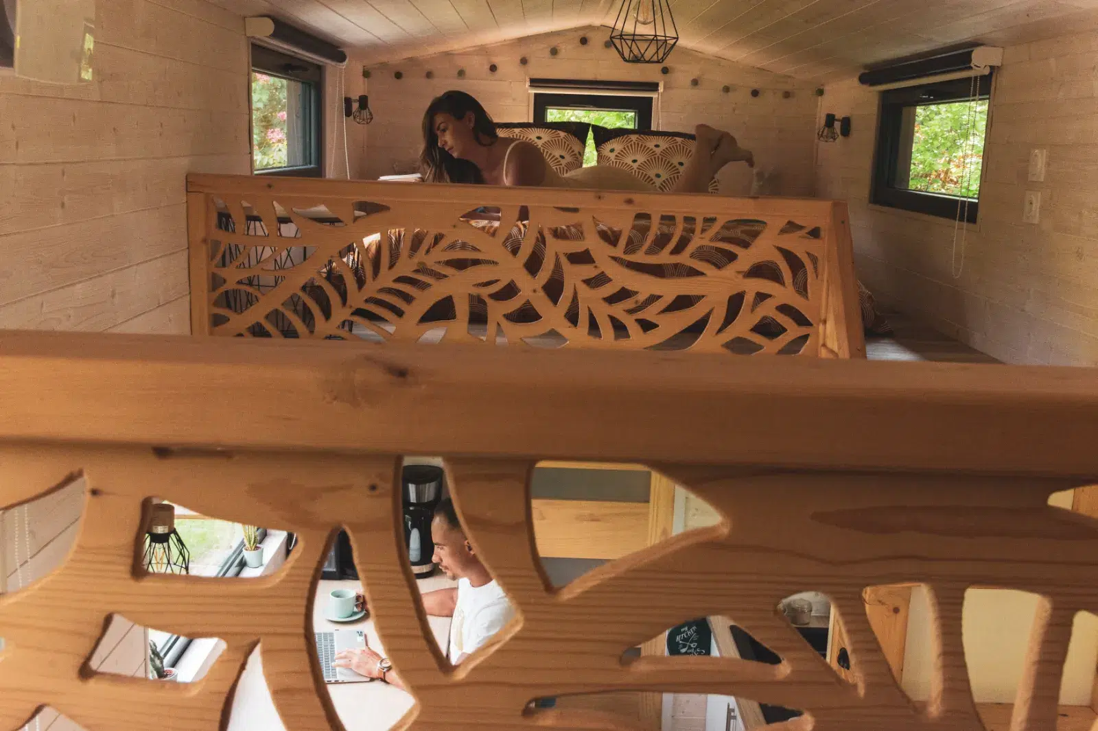 Jardin arboré avec brasero et chaises en bois devant un gîte moderne